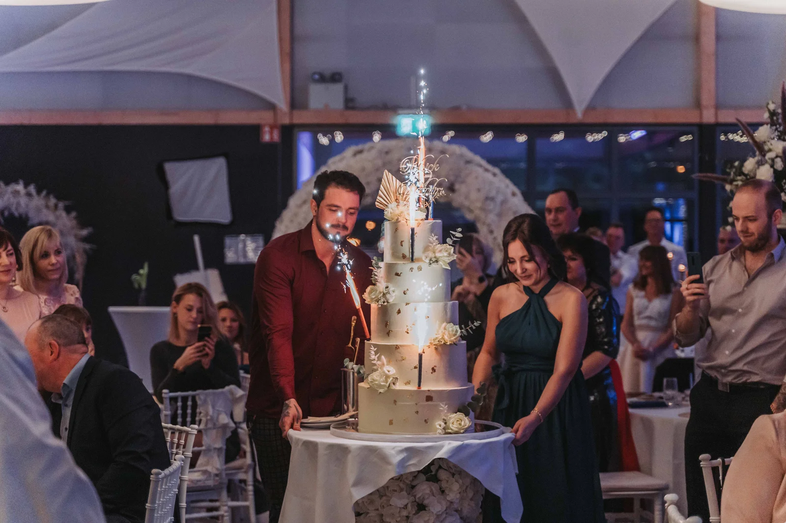 Brautpaar vor beeindruckender mehrstöckiger Hochzeitstorte mit Wunderkerzen